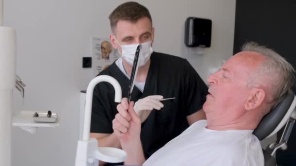 Ένας Γκριζομάλλης Συνταξιούχος Που Κάθεται Καρέκλα Οδοντιάτρου Μιλάει Για Οδοντιατρικά — Αρχείο Βίντεο