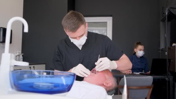 Dentista Trabalha Com Homem Mais Velho Examinando Seus Dentes Clínica — Vídeo de Stock