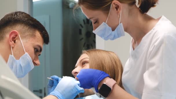 Tandläkaren Och Hans Assistent Undersöker Munhålan Och Behandlar Klienten Tandvård — Stockvideo