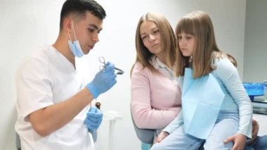 Şefkatli dişçi anne ve çocuğa danışıyor. Ebeveynlerle doktoru ziyaret etmek, diş hekimi korkusu, tıbbi bakım konsepti. Yüksek kalite 4k video