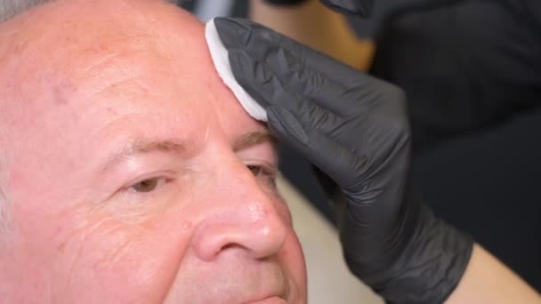 一位老年男子在一位美容师的检查中 坐在现代诊所的椅子上 注射治疗皱纹的疗效观察 — 图库视频影像