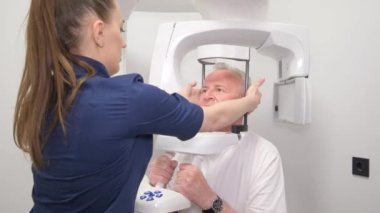 Doktor yaşlı bir insanın kafasının röntgenini çeker. Yüzünden estetik ameliyat hazırlığı