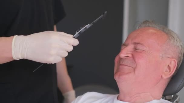 外科医は老人の前にいて 顔に印をつけている 医者は顔にマークを作るために永久的なマーカーを使用し その後 整形手術のためにそれらを準備します — ストック動画