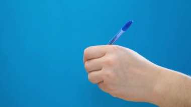 Genç bir adam arka planda tükenmez kalemle bir şeyler yazıyor. Elle yazma. Solak. Mavi kromakey