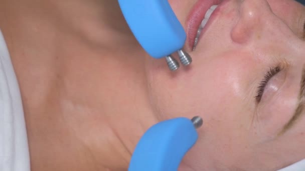 近代的な美容クリニックでマイクロカレント療法を使用して顔の皮膚の若返り ハードウェア化粧品学 美容室での女性の顔のケア — ストック動画