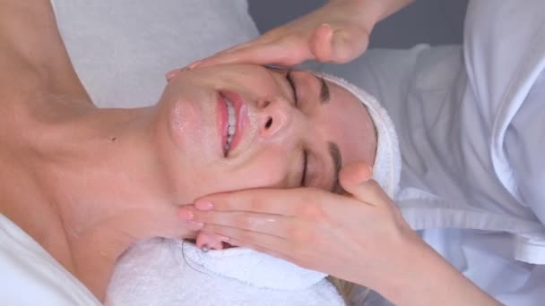 お客様の顔に保湿マスクを適用し ぬれた顔のマッサージを行う美容師 アンチエイジングフェイシャルマッサージを楽しむ女 — ストック動画