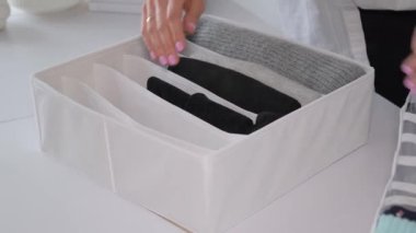 Kadınların elleri dikkatlice giysileri sepete katlar. Temizlik, temizlik, dağınıklık, düzenleme....