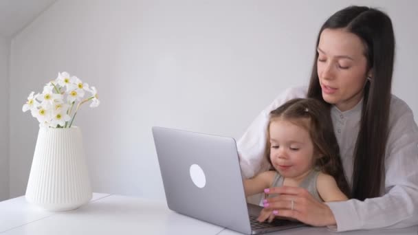 幸せな若い自営業の母親が自宅からリモートワークを楽しんでいますかわいい赤ちゃんの女の子が一緒にラップトップの前に座って — ストック動画