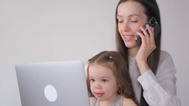 小さな娘と一緒に幸せな母親は家でリモートで働いています スマートフォン経由の通信事業 — ストック動画