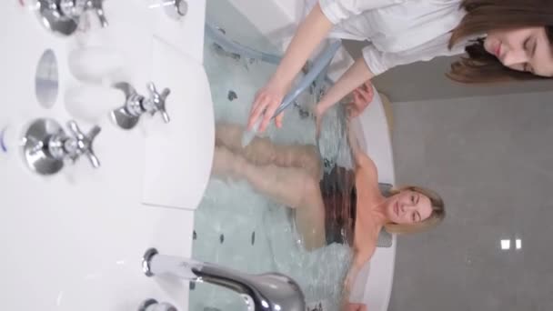 美しい女性は ハイドロマッサージ風呂で手順を実行します 温泉で治療を受けているリラックスした女性 垂直ビデオ — ストック動画