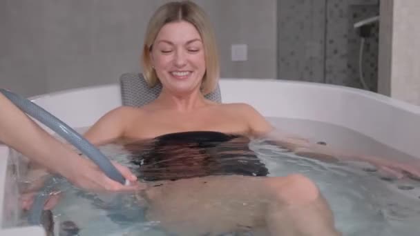 専門医は女性にハイドロマッサージを与えます 薬と特別な風呂でのハイドロマッサージ手順 モダンなスパサロン — ストック動画