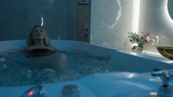 客室内にはカラフルな照明が設置されたジャグジーでリラックスした美しい女性 熱い浴槽でリラックス — ストック動画