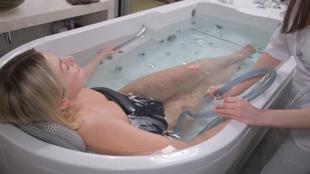 専門医は女性にハイドロマッサージを与えます 薬と特別な風呂でのハイドロマッサージ手順 モダンなスパサロン — ストック動画