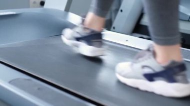 Spor salonunda yavaş adımlarla koşu bandında egzersiz yapan aktif bir kadın. Spor salonunda çalışan fitness kızı.