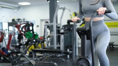 Spor salonunda bisiklet süren aktif bir kadın. Ağır çekimde esmer kadın eğitimi. Spor salonunda çalışan fitness kızı.