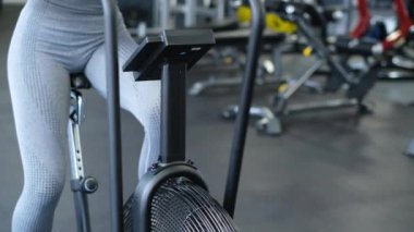 Spor salonunda bisiklet süren aktif bir kadın. Ağır çekimde esmer kadın eğitimi. Spor salonunda çalışan fitness kızı.