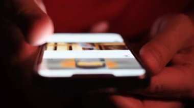 Akıllı telefonlu bir adamın elinin yakın çekimi. Bir adam internette haberleri izliyor.