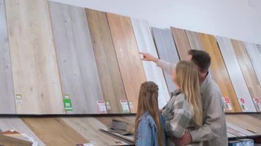 Hırdavatçıdaki genç bir aile, ev yenileme ve yeni tasarım fikirleri için ahşap kaplama bir yüzey seçiyor. Yeni bir evde yenileme konsepti