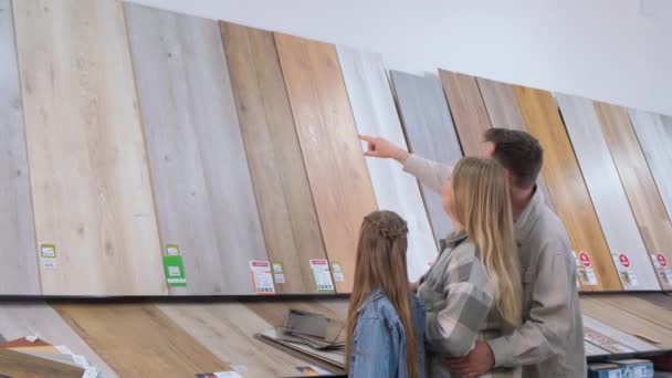 ハードウェアストアの若い家族は 家庭の改装や新しいデザインのアイデアのための木製のラミネート表面を選択します 新しい家の改装の概念 — ストック動画