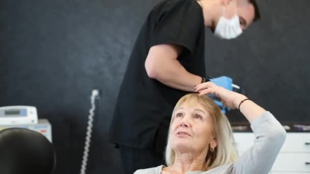 整形手术前面部有穿孔的漂亮老妇人 美容师摸女人的脸 用记号画画 面部整形手术的概念 — 图库视频影像