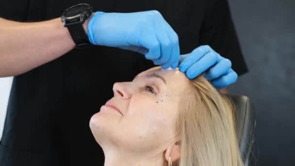 資格の美容師は 現代のクリニックで高齢女性の顧客のための若返りと顔の皮膚引き締めのための美容注射を実行します — ストック動画