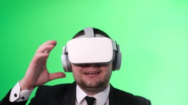 Mutlu ofis çalışanı stüdyodaki yeşil arka planda sanal gerçeklik kulaklığı kullanıyor..