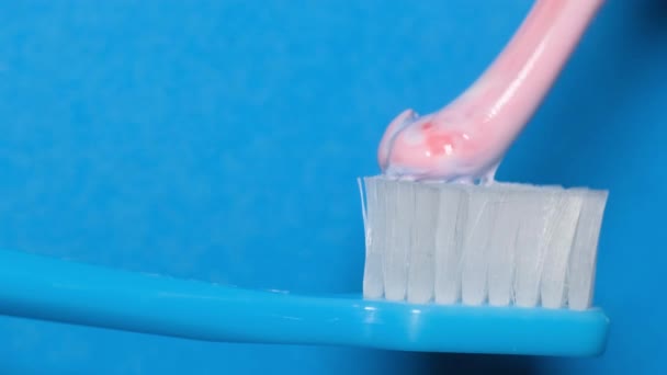 青の背景にブラシに歯磨き粉を絞るマクロビデオ 歯や口腔の清潔感の概念 — ストック動画