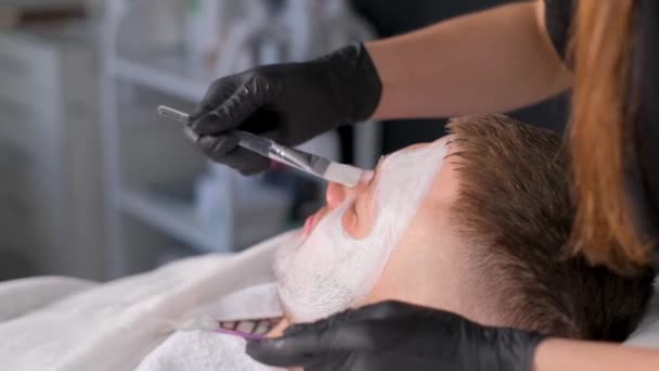 美容师用黏土面罩按摩脸部 在温泉疗养院里接受面部治疗的男人 — 图库视频影像