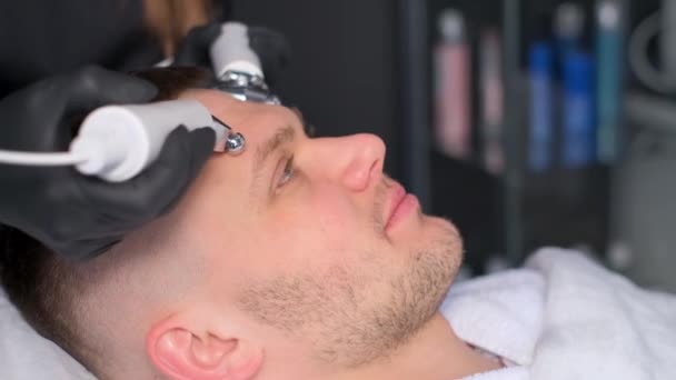 女性の美容師がキャビテーションの手順を実行します 男性の顔の皮膚の若返り — ストック動画