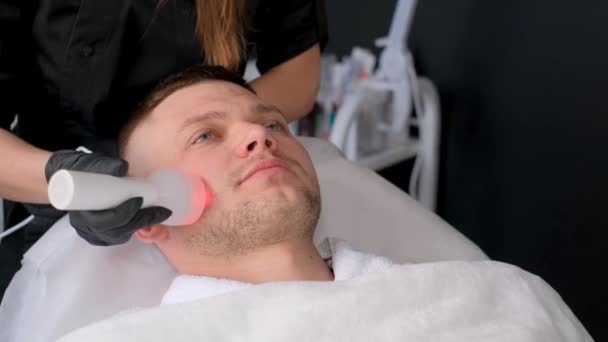 女性の美容師は フォノフォシス手順を実行します 男性の顔の皮膚の若返り 美容師は超音波スキンリフティングを実行します — ストック動画