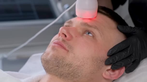 美容師はフォノフォシス手順を実行します 男性の顔の皮膚の若返り 超音波皮膚リフティング 閉じろ — ストック動画