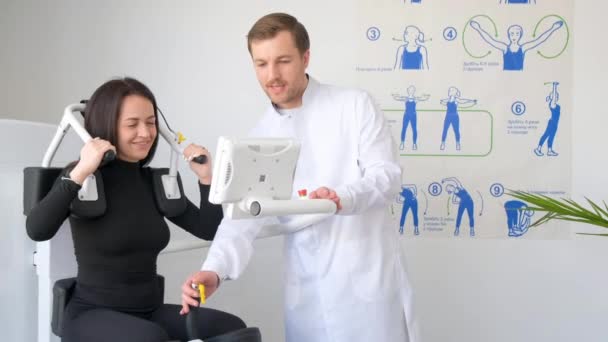 一位年轻妇女正在与理疗师一起在一台诊断机器上做脊柱检查 脊椎专家的专业工作 预防脊柱疾病 — 图库视频影像