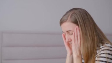 Kafası aşağıda ve elleri yüzünün önünde sıkıca bağlanmış bir kadın. Umutsuzluk, depresyon, migren veya baş ağrısı bakışı.