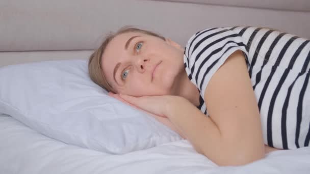 落ち込んでいる女性が目を閉じてベッドの上に横たわっている 家で休もう — ストック動画