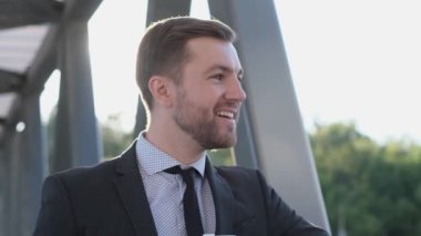 Kameraya gülümseyen bir iş adamı. Güneş ışınlarının arka planında. Erkek müdür dışarıda..