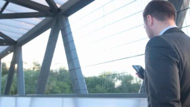 Beyaz bir işadamının ofis merkezinin yakınında yürürken ve telefonda konuşurken yan görüntüsü. Yakından. Dışarıdan.