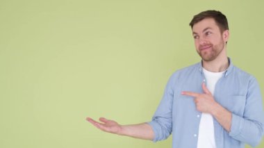 Genç mutlu adam kameraya bakıyor, elleri ve kolları iş yerinde yana bakıyor, sade stüdyo arka planında izole edilmiş bir model..