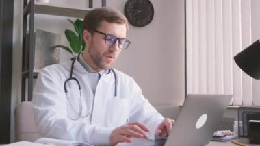 Avrupa görünümlü genç bir doktor ofiste oturuyor ve bilgisayar başında çalışıyor. Doktor dizüstü bilgisayardaki işini bitirir. Yoğun bir iş. Yorgun doktor. Baş ağrısı