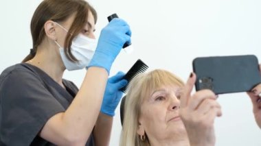 Doktor saç yapısına teşhis koyuyor. Yaşlı bir kadının trikoloğa danışması.