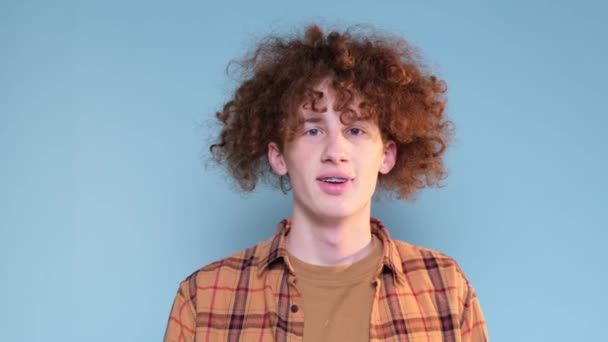 Mavi Arka Planda Kıvırcık Kızıl Saçlı Genç Bir Adamın Portresi — Stok video