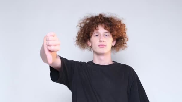 Ung Rödhårig Lockig Student Ljus Bakgrund Visar Ett Finger Ner — Stockvideo