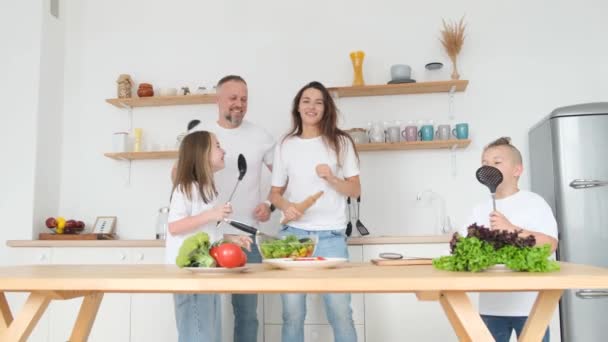 朝食を準備しながら キッチンで陽気な家族のダンス 息子と娘は両親と楽しい時間を過ごし 一緒に料理をして歌います — ストック動画