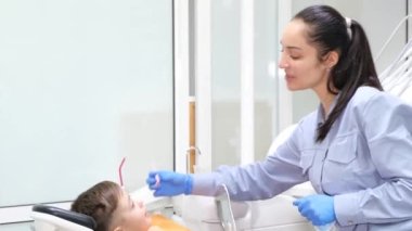 Küçük bir çocukla dişçi muayenesi sırasında genç ve çekici bir dişçi. Modern pediatrik dişçilik.