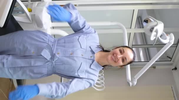 垂直录像 一个穿着医疗制服的漂亮微笑的年轻女牙医的画像 牙医在工作 工作满意度 — 图库视频影像