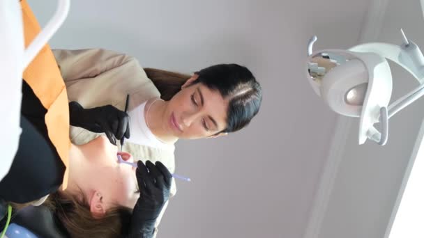 垂直录像 一位年轻的女牙医治疗一位坐在现代牙科诊所的年轻病人的牙齿 现代牙科技术 — 图库视频影像