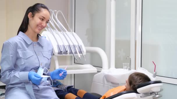 在与小男孩的一次牙科咨询中 快乐的微笑着的女牙医 儿童的牙科学 儿童的牙科治疗 — 图库视频影像
