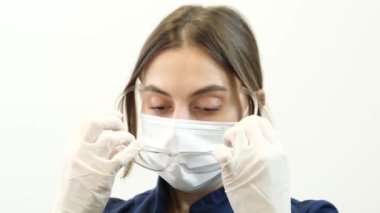 Dişçilerin yüzüne yakın çekim. Beyaz arka planda koruyucu maskeli ve gözlüklü bir kadın dişçi. İşten önce dişçi