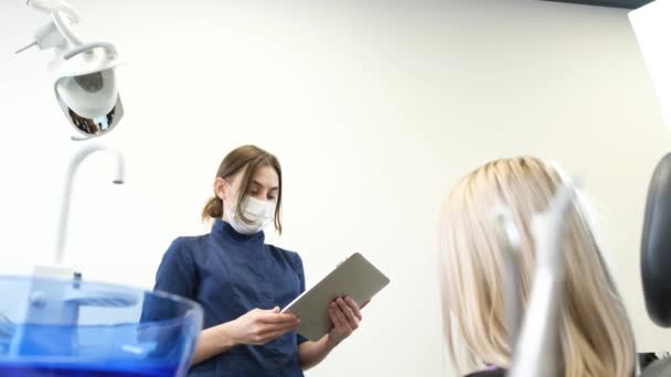 在一间现代化的办公室里 牙医预约时 金发碧眼的金发女郎 女牙医用石碑咨询病人 — 图库视频影像