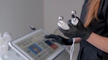 Kozmetolojide modern donanım cihazları. Bir kozmetolog, bir dermatolog kozmetoloji kliniğinde elektrikli silindir masaj aleti ayarlıyor..
