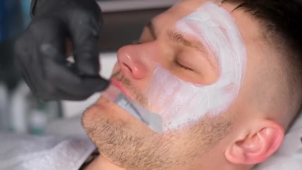 顔にマスクをつけながらリラックスした男の顔のクローズアップ 美容師との約束で男 男性のにきびの治療 — ストック動画